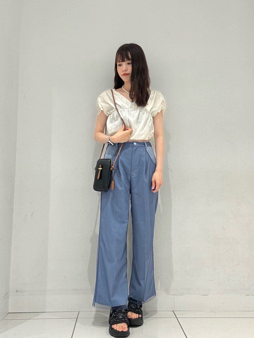 ブルー系のその他パンツ、ホワイト系のシャツ/ブラウス、ブラック系のショルダーバッグを着用したレディースの夏コーディネートの2枚目の写真