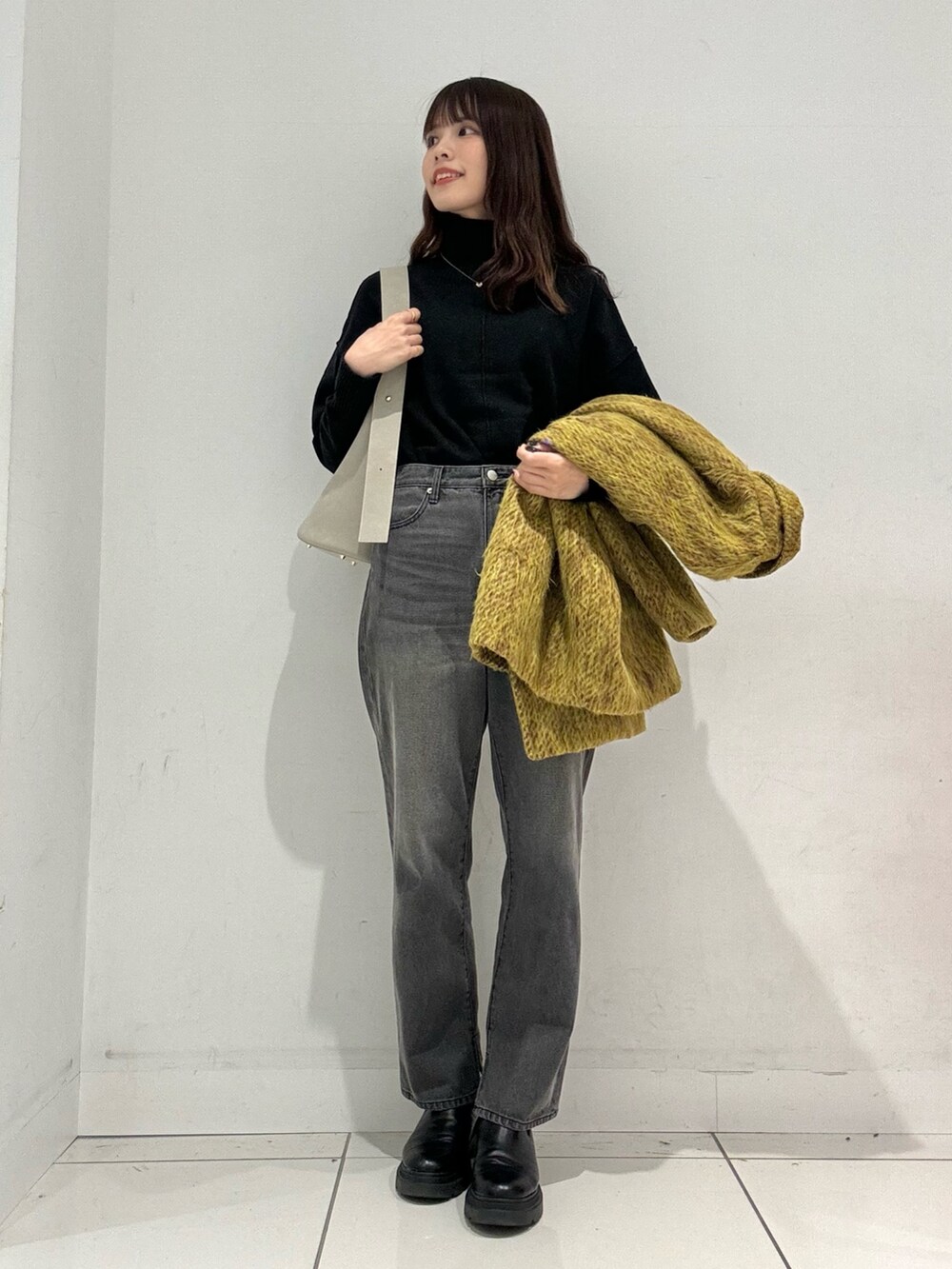 イエロー系のステンカラーコート、グレー系のその他パンツ、ベージュ系のハンドバッグを着用したレディースの秋コーディネートの5枚目の写真