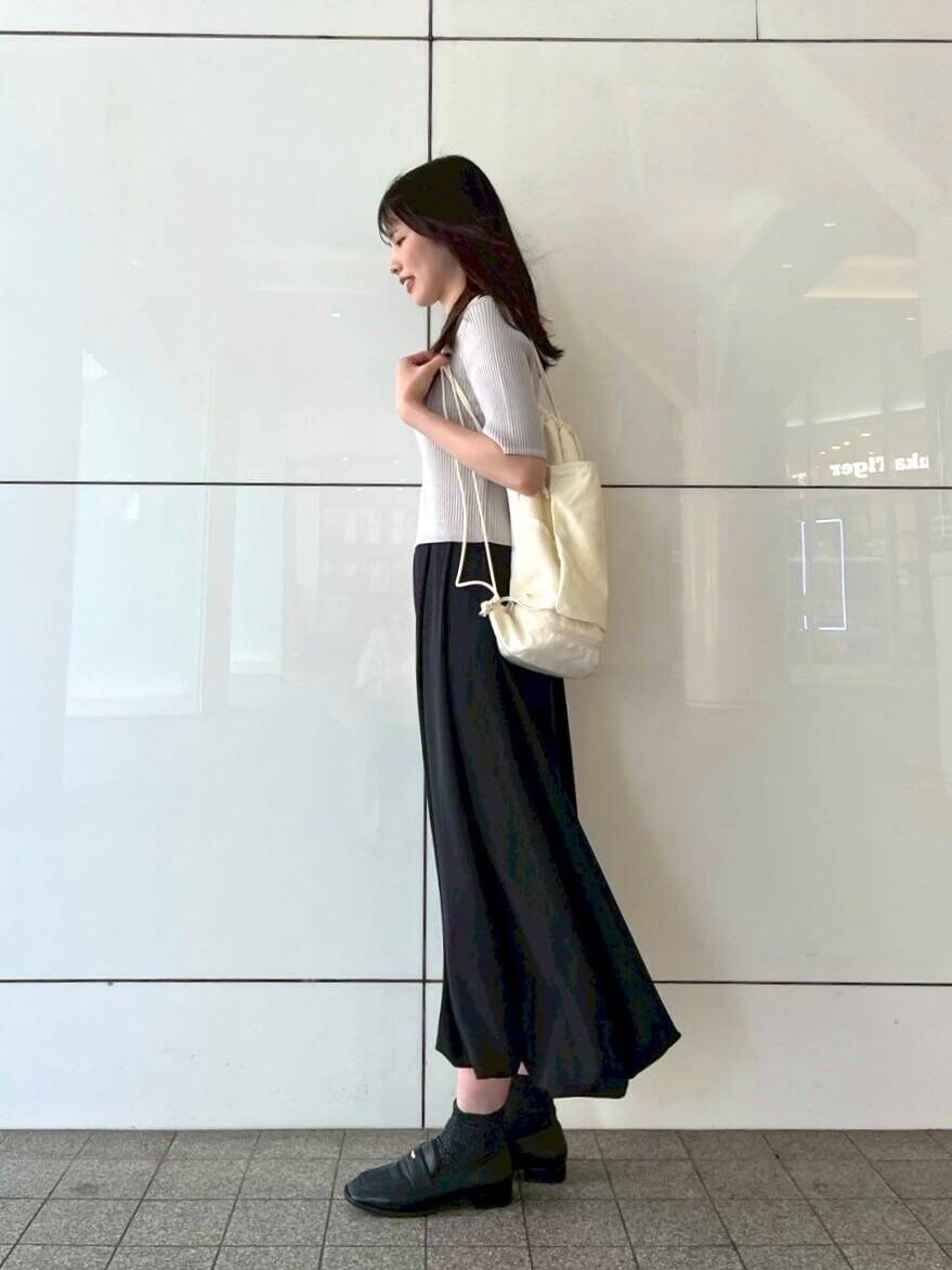 ブラック系のスカート、ブラック系のローファー、ホワイト系のショルダーバッグを着用したレディースの春コーディネートの2枚目の写真