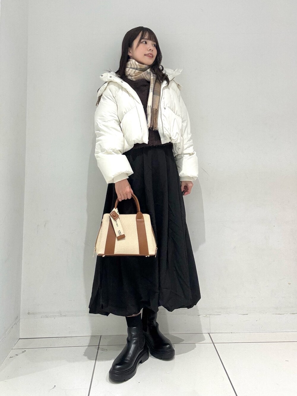 ブラック系のスカート、ブラウン系のニット/セーター、ホワイト系のダウンジャケット/コートを着用したレディースの冬コーディネートの5枚目の写真