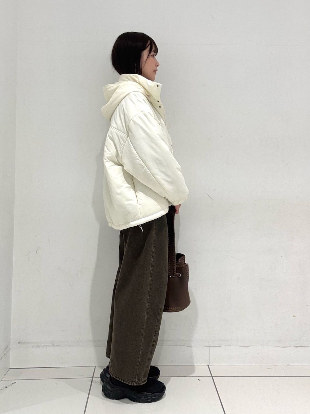 ホワイト系のダウンジャケット/コート、ブルー系のニット/セーター、ブラウン系のデニムパンツを着用したレディースの秋コーディネートの2枚目の写真