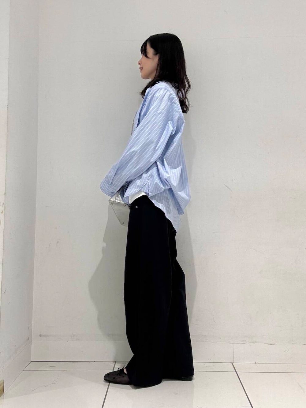 ブラック系のバレエシューズ、シルバー系のボストンバッグ、ブルー系のシャツ/ブラウスを着用したレディースの冬コーディネートの2枚目の写真