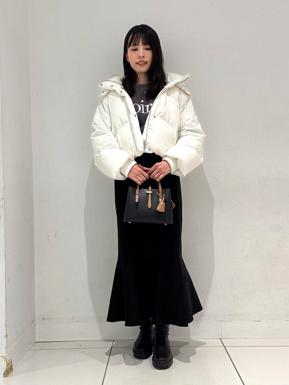 グレー系のニット/セーター、ホワイト系のダウンジャケット/コート、ブラック系のハンドバッグを着用したレディースの冬コーディネートの4枚目の写真