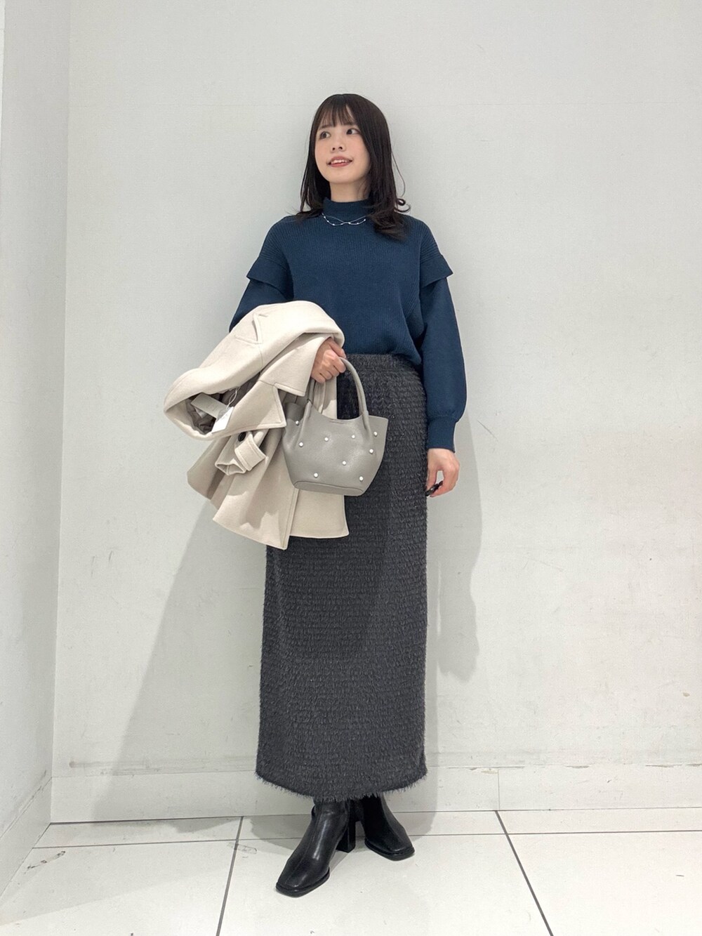 ブルー系のニット/セーター、ベージュ系のその他アウター、グレー系のスカートを着用したレディースの冬コーディネートの5枚目の写真