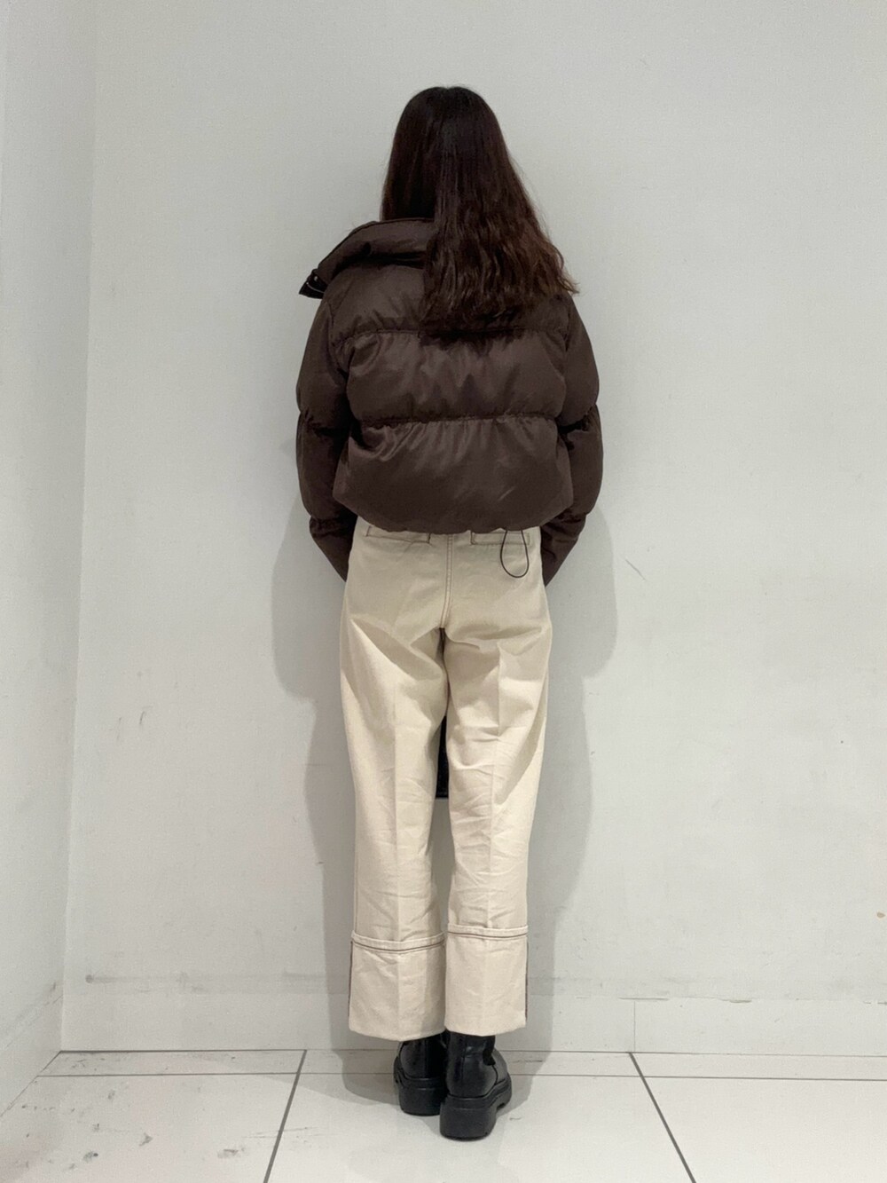 ブラック系のニット/セーター、ブラウン系のダウンジャケット/コート、ホワイト系のデニムパンツを着用したレディースの秋コーディネートの3枚目の写真