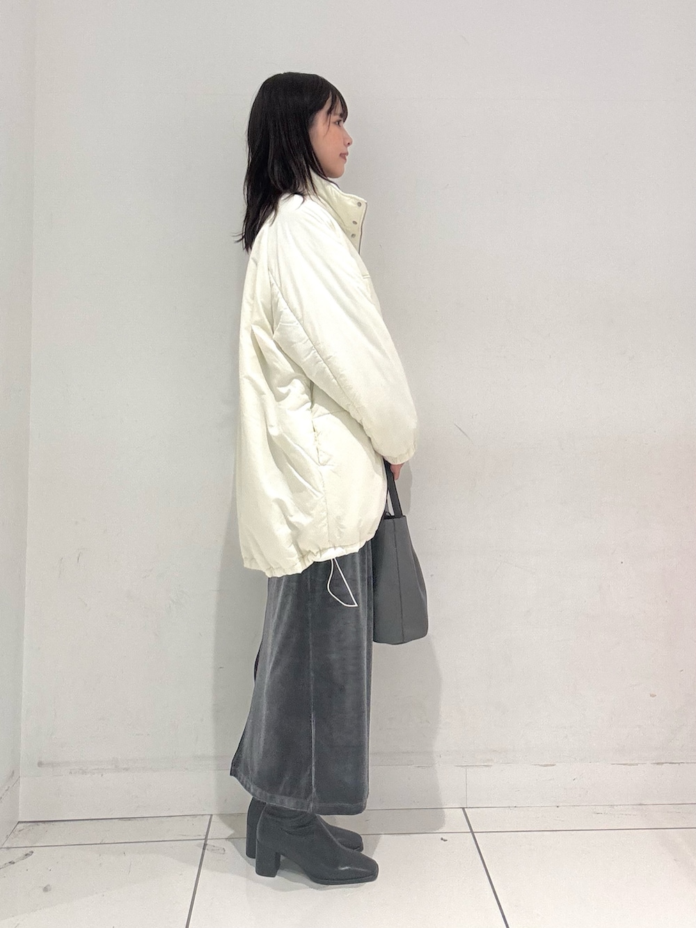 ブルー系のニット/セーター、ホワイト系のダウンジャケット/コート、グレー系のスカートを着用したレディースの秋コーディネートの2枚目の写真