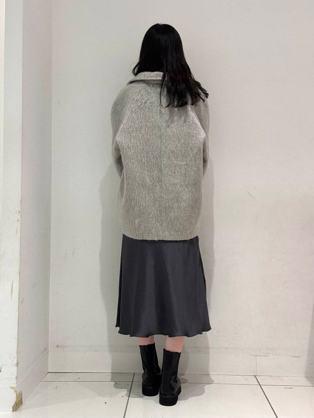 グレー系のスカート、ブラック系のブーツ、ブラック系のハンドバッグを着用したレディースの冬コーディネートの3枚目の写真