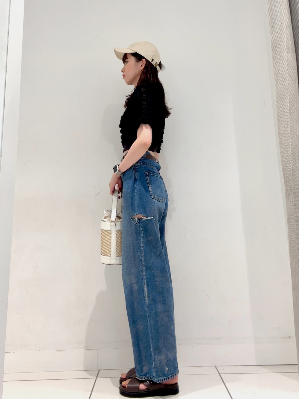 ブルー系のデニムパンツ、ブラック系のTシャツ/カットソー、ホワイト系のショルダーバッグを着用したレディースの夏コーディネートの2枚目の写真