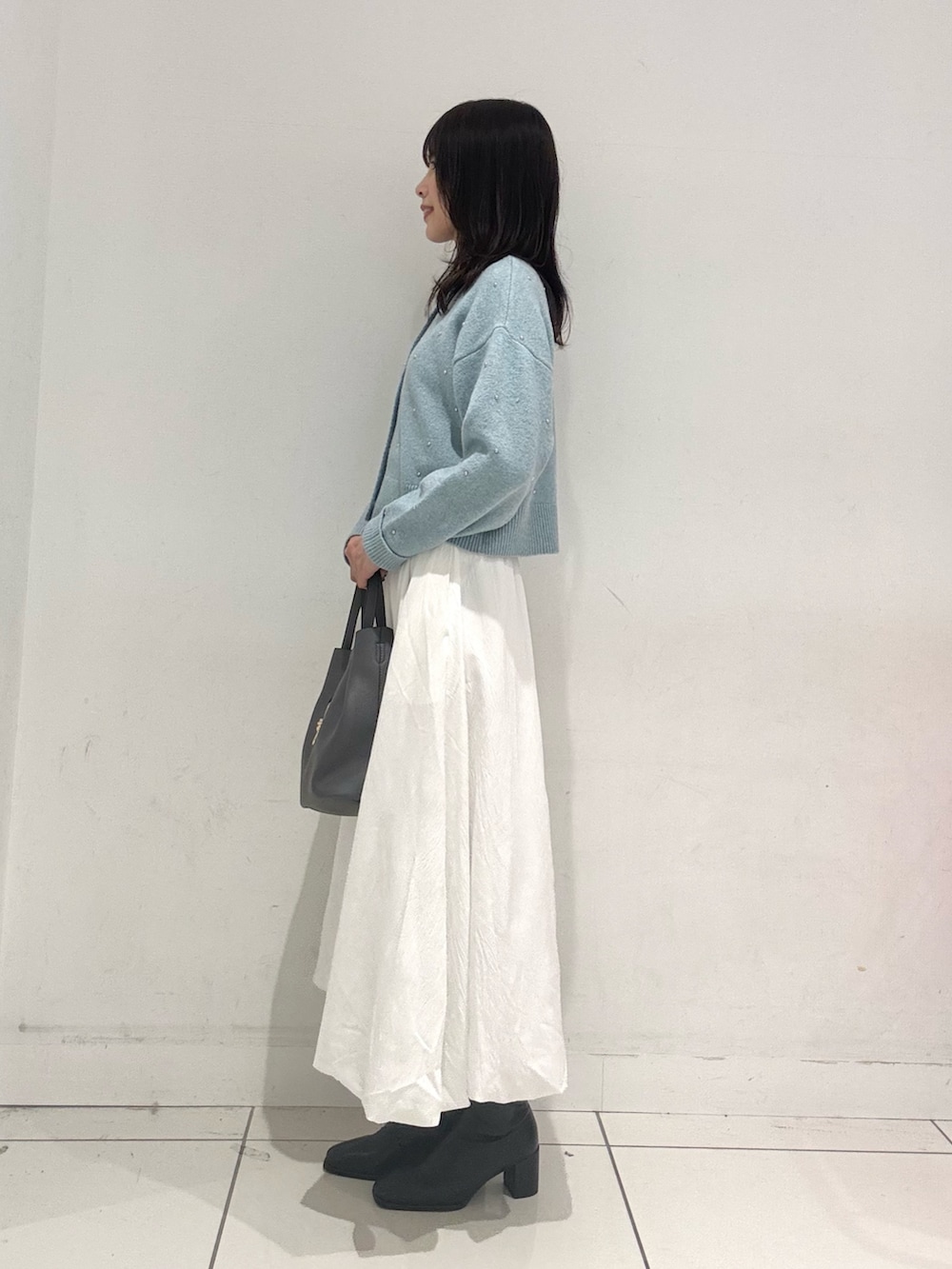 ホワイト系のスカート、グレー系のトートバッグ、ブラック系のブーツを着用したレディースの秋コーディネートの2枚目の写真