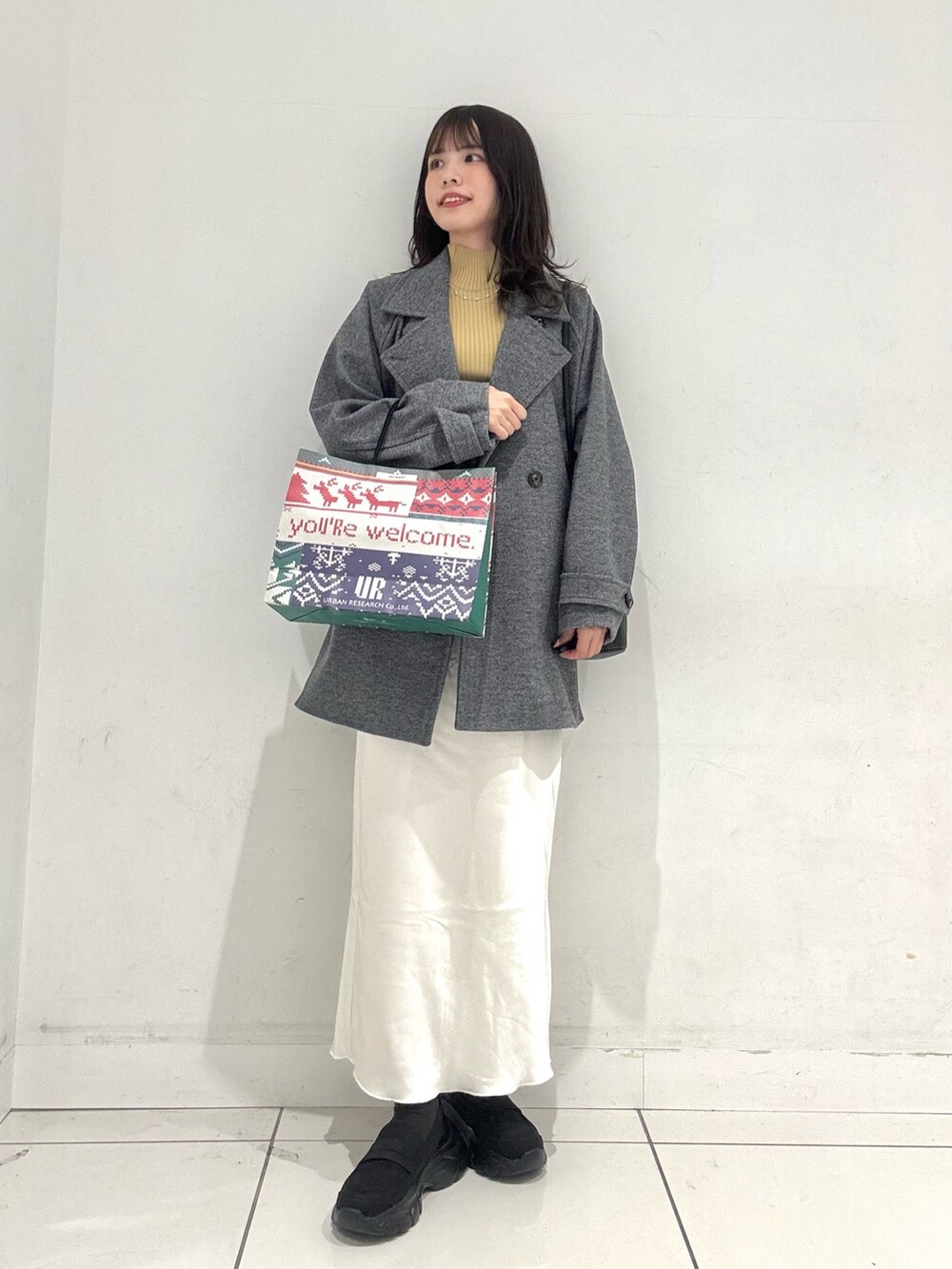 グレー系のその他アウター、イエロー系のニット/セーター、ホワイト系のスカートを着用したレディースの冬コーディネートの5枚目の写真