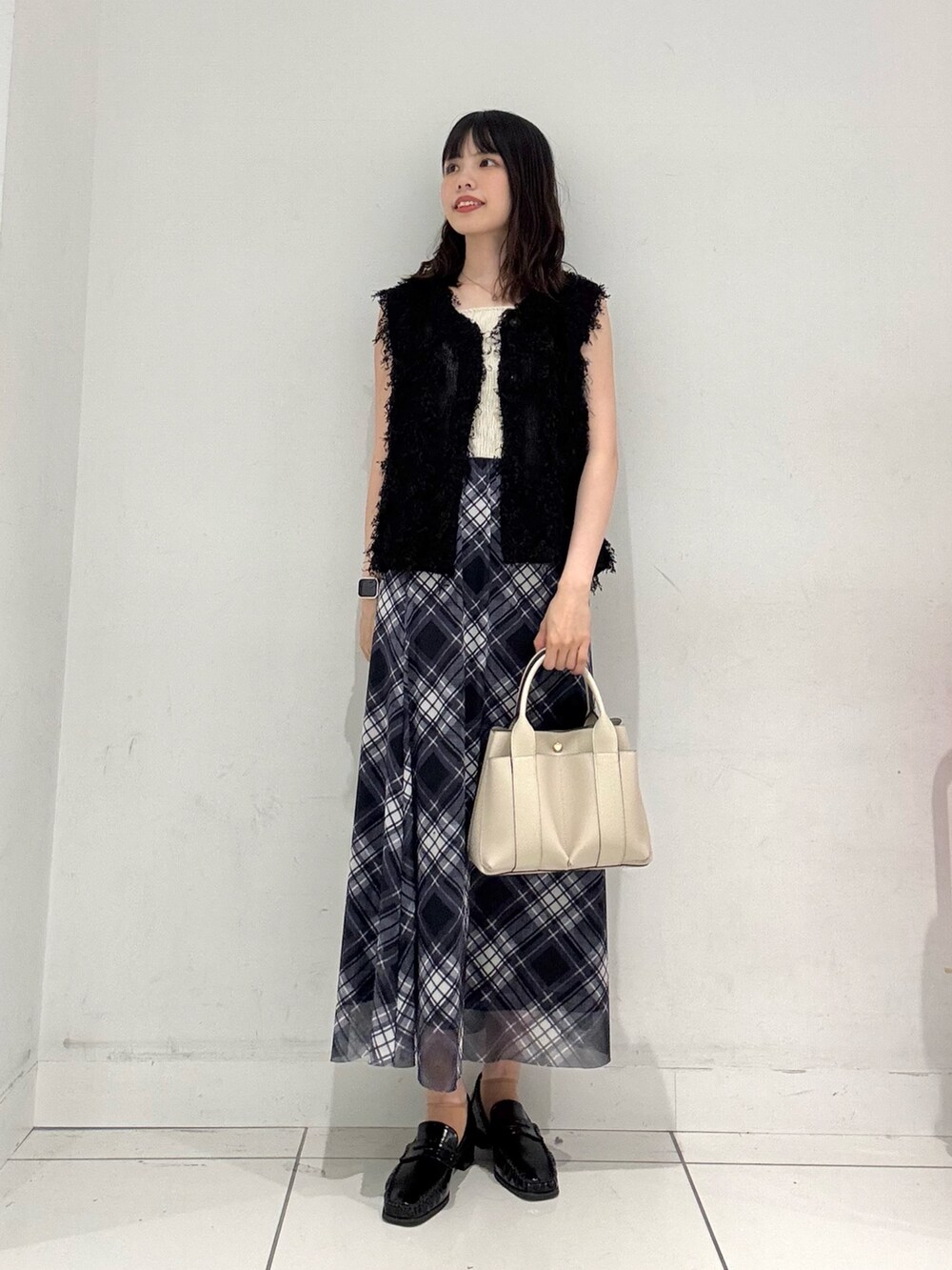 ブラック系のベスト、ホワイト系のキャミソール、ブルー系のスカートを着用したレディースの夏コーディネートの4枚目の写真