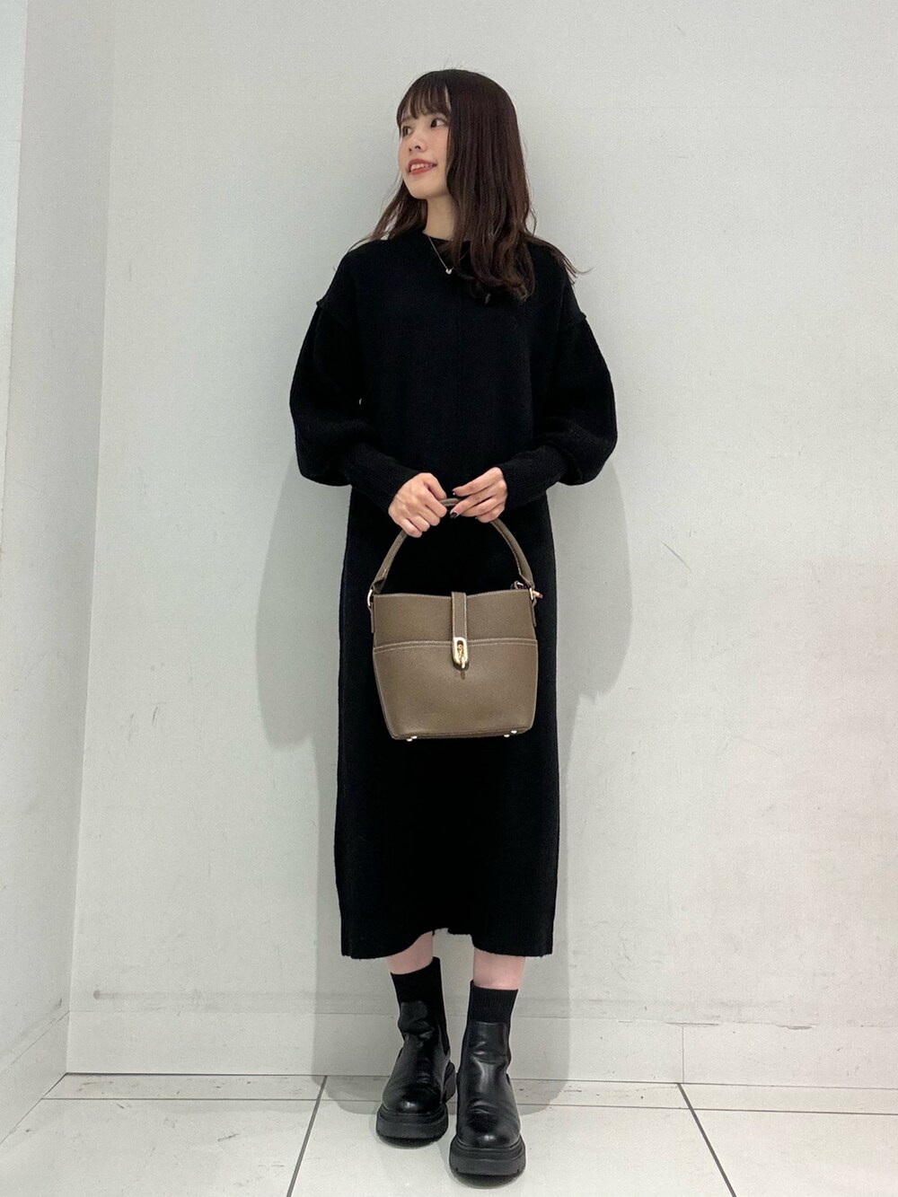 ブラック系のワンピース、ベージュ系のハンドバッグ、ベージュ系のその他アウターを着用したレディースの秋コーディネートの6枚目の写真