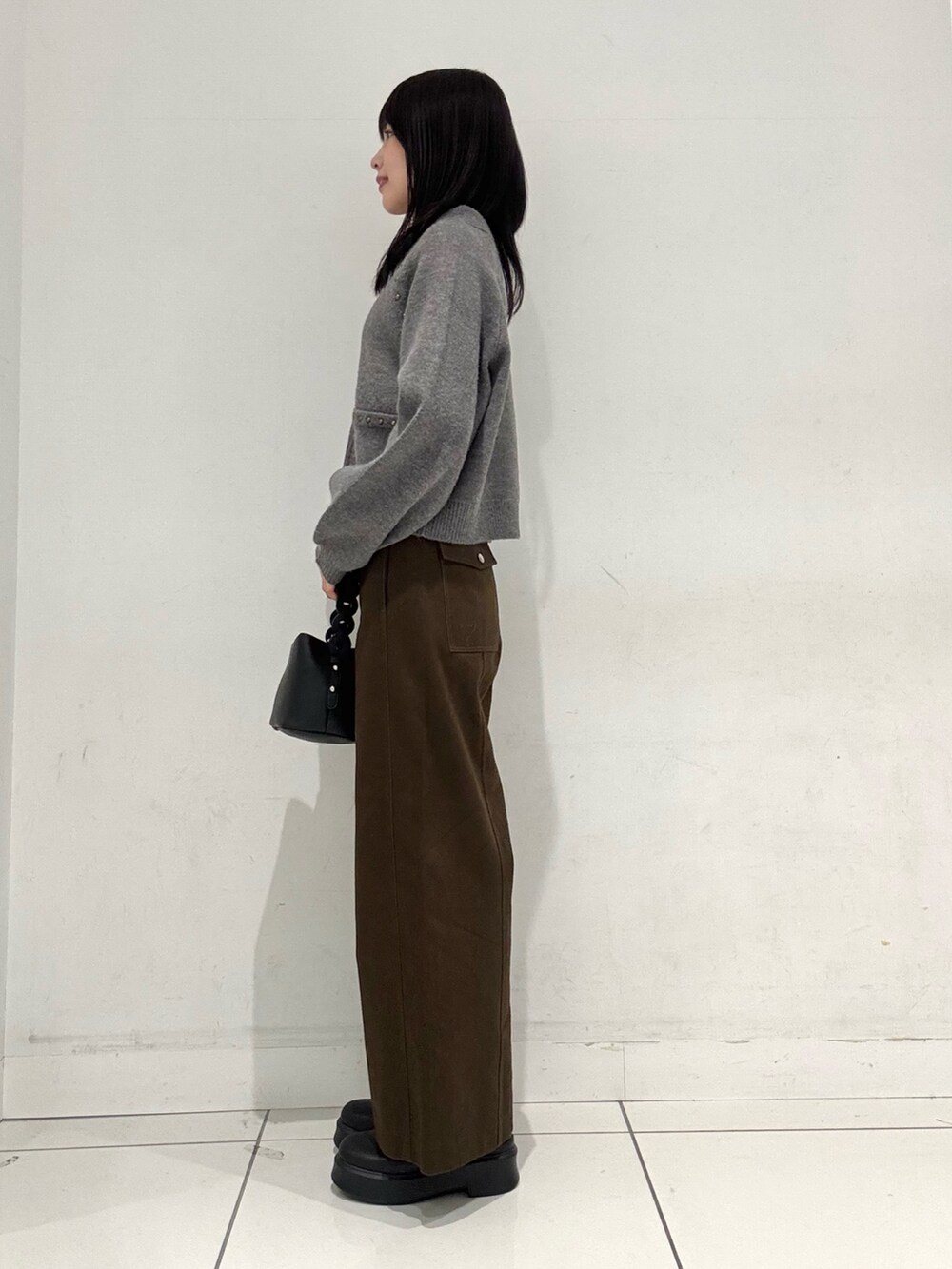 グレー系のカーディガン/ボレロ、ホワイト系のTシャツ/カットソー、ブラック系のショルダーバッグを着用したレディースの冬コーディネートの2枚目の写真