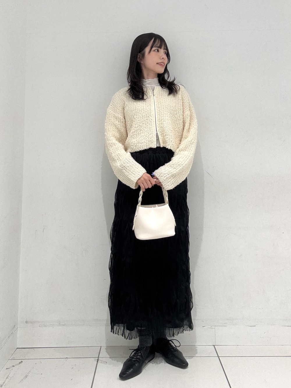 ホワイト系のTシャツ/カットソー、ホワイト系のカーディガン/ボレロ、ブラック系のスカートを着用したレディースの冬コーディネートの4枚目の写真
