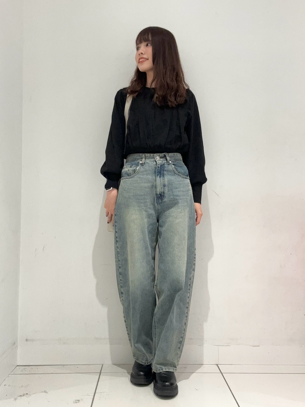 ブルー系のデニムパンツ、ブラック系のニット/セーター、ベージュ系のショルダーバッグを着用したレディースの秋コーディネートの4枚目の写真