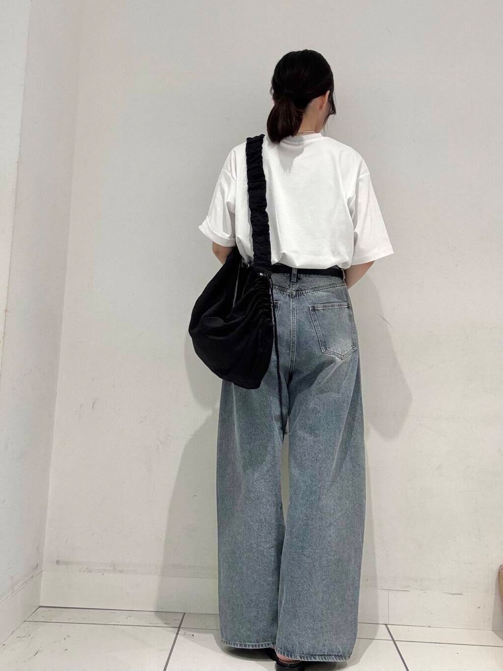 ブラック系のショルダーバッグ、ブラック系のサンダル、ブルー系のデニムパンツを着用したレディースの春コーディネートの3枚目の写真