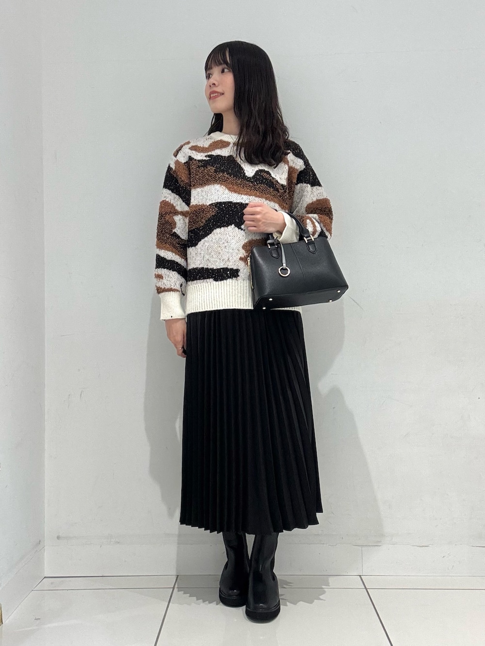 ホワイト系のニット/セーター、ブラック系のスカート、ブラック系のハンドバッグを着用したレディースの冬コーディネートの4枚目の写真