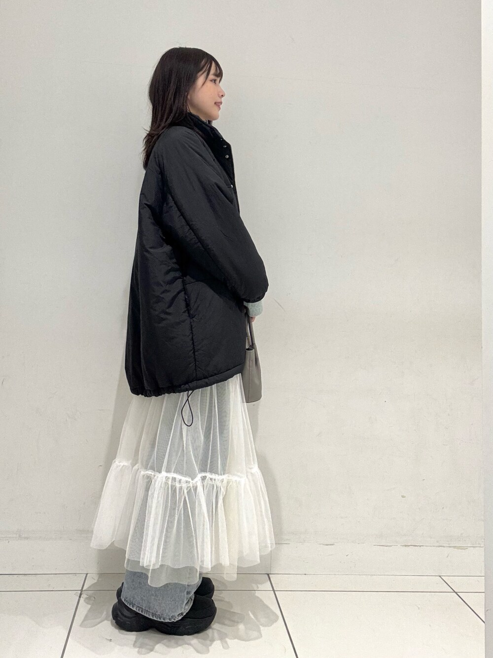 ホワイト系のTシャツ/カットソー、グリーン系のニット/セーター、ホワイト系のスカートを着用したレディースの冬コーディネートの2枚目の写真