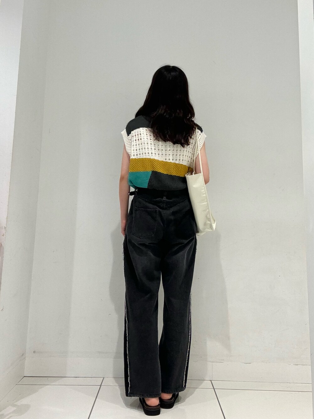 ブラウン系のサンダル、ブラック系のデニムパンツ、グレー系のベストを着用したレディースの夏コーディネートの4枚目の写真