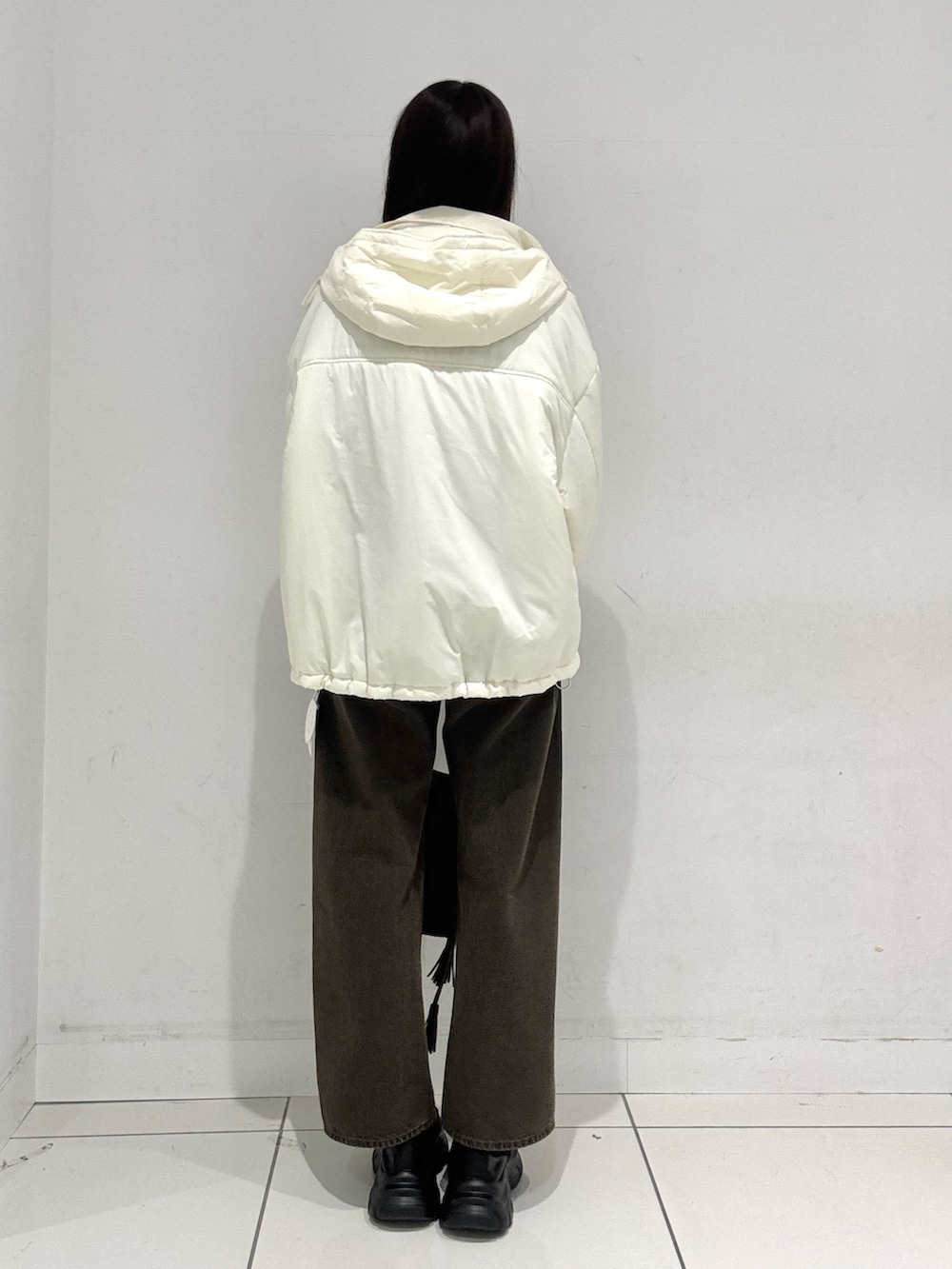 ホワイト系のダウンジャケット/コート、ブルー系のニット/セーター、ブラウン系のデニムパンツを着用したレディースの秋コーディネートの3枚目の写真