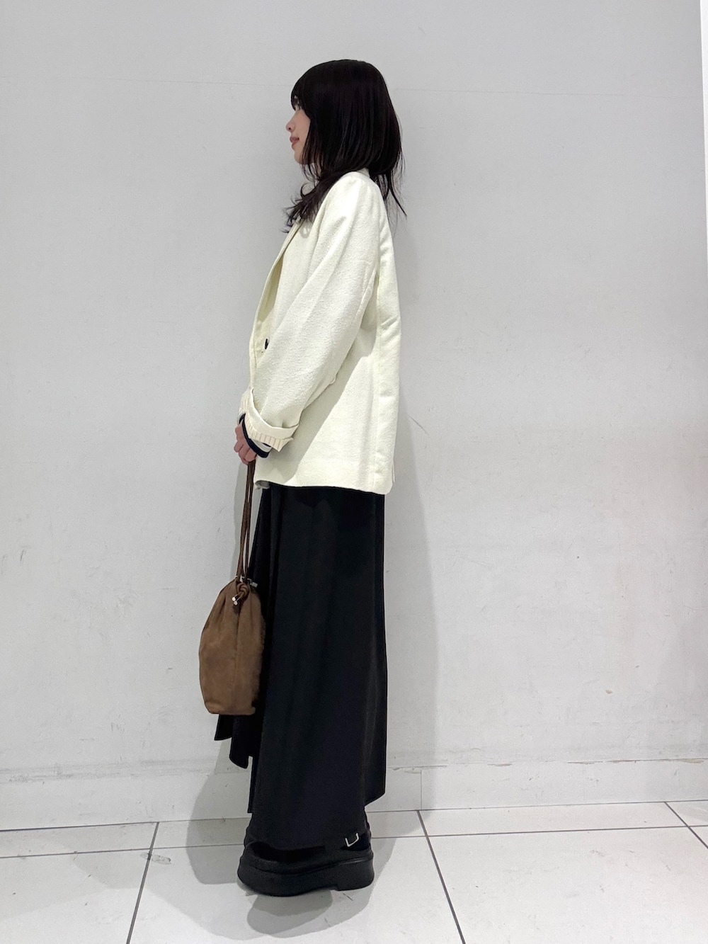 ブルー系のTシャツ/カットソー、ホワイト系のテーラードジャケット、ブラウン系のハンドバッグを着用したレディースの冬コーディネートの2枚目の写真