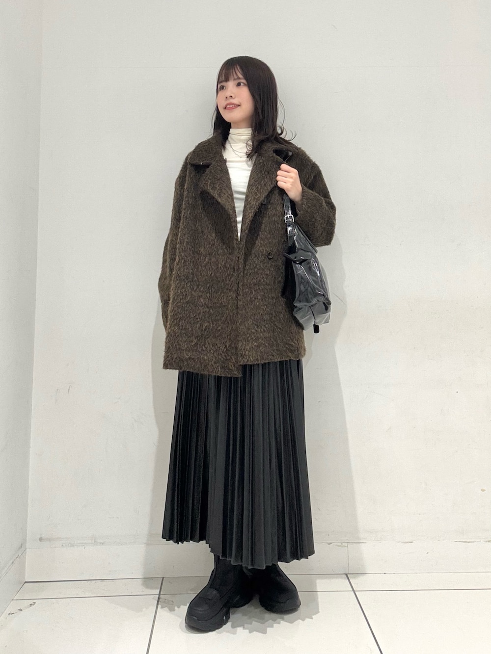 ホワイト系のTシャツ/カットソー、ブラック系のスカート、ブラック系のその他シューズを着用したレディースの冬コーディネートの4枚目の写真