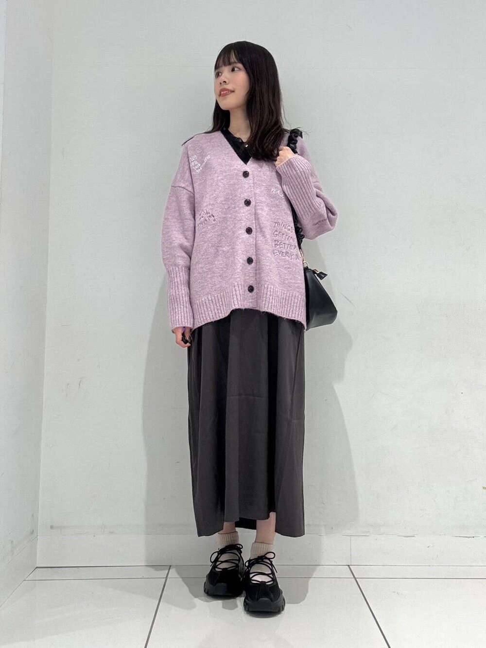 ブラック系のショルダーバッグ、グレー系のワンピース、ブラック系のスニーカーを着用したレディースの冬コーディネートの4枚目の写真