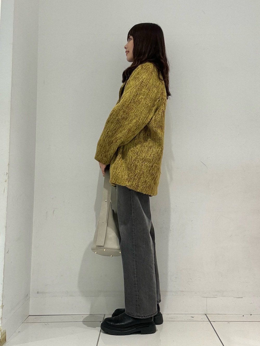 イエロー系のステンカラーコート、グレー系のその他パンツ、ベージュ系のハンドバッグを着用したレディースの秋コーディネートの2枚目の写真