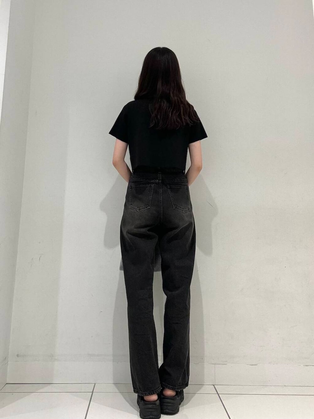 ブラック系のニット/セーター、シルバー系のトートバッグ、ブラック系のデニムパンツを着用したレディースの夏コーディネートの4枚目の写真