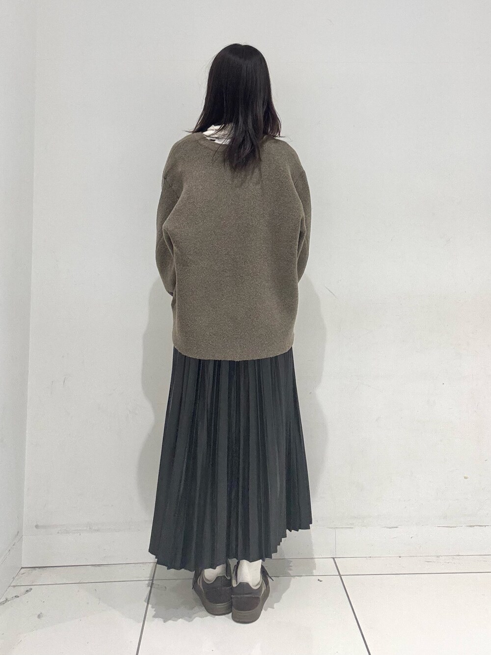 ブラック系のスカート、ブラウン系のその他アウター、ホワイト系のニット/セーターを着用したレディースの秋コーディネートの3枚目の写真