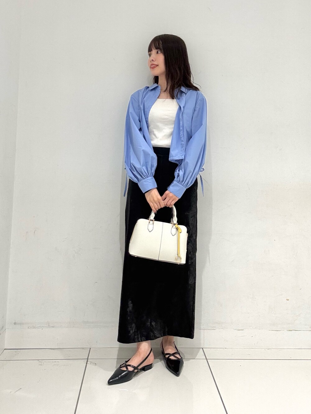 ブルー系のシャツ/ブラウス、ブラック系のスカート、ホワイト系のハンドバッグを着用したレディースの秋コーディネートの4枚目の写真