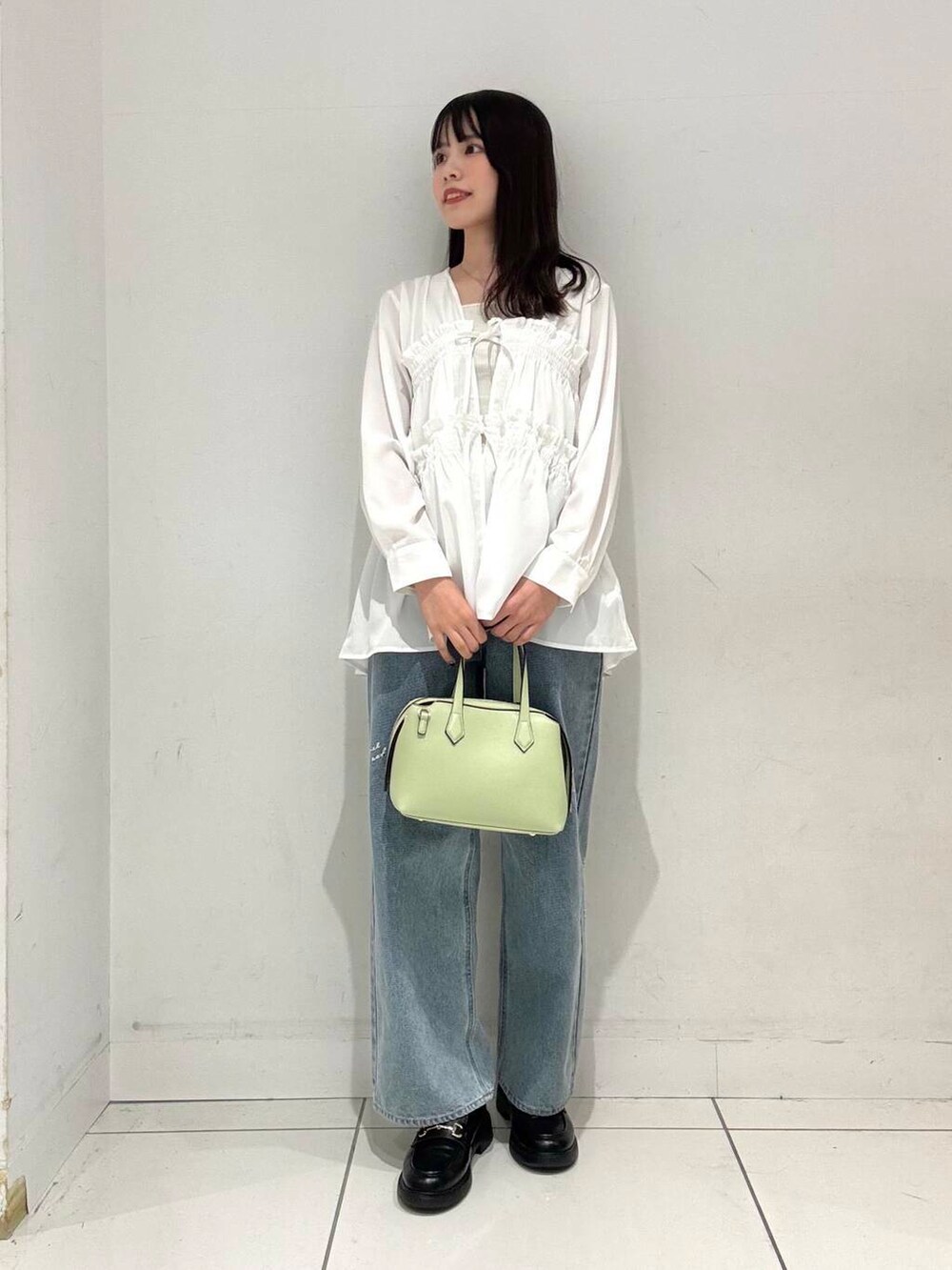 グリーン系のトートバッグ、ブルー系のデニムパンツ、ホワイト系のシャツ/ブラウスを着用したレディースの春コーディネートの4枚目の写真