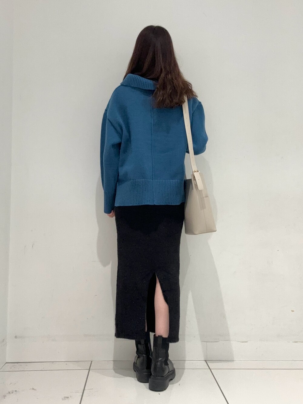 ブルー系のニット/セーター、ブラック系のスカート、ベージュ系のショルダーバッグを着用したレディースの秋コーディネートの3枚目の写真