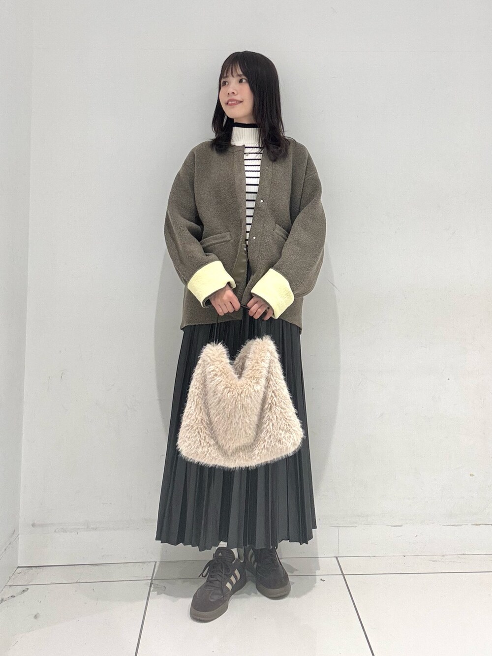 ブラック系のスカート、ブラウン系のその他アウター、ホワイト系のニット/セーターを着用したレディースの秋コーディネートの4枚目の写真