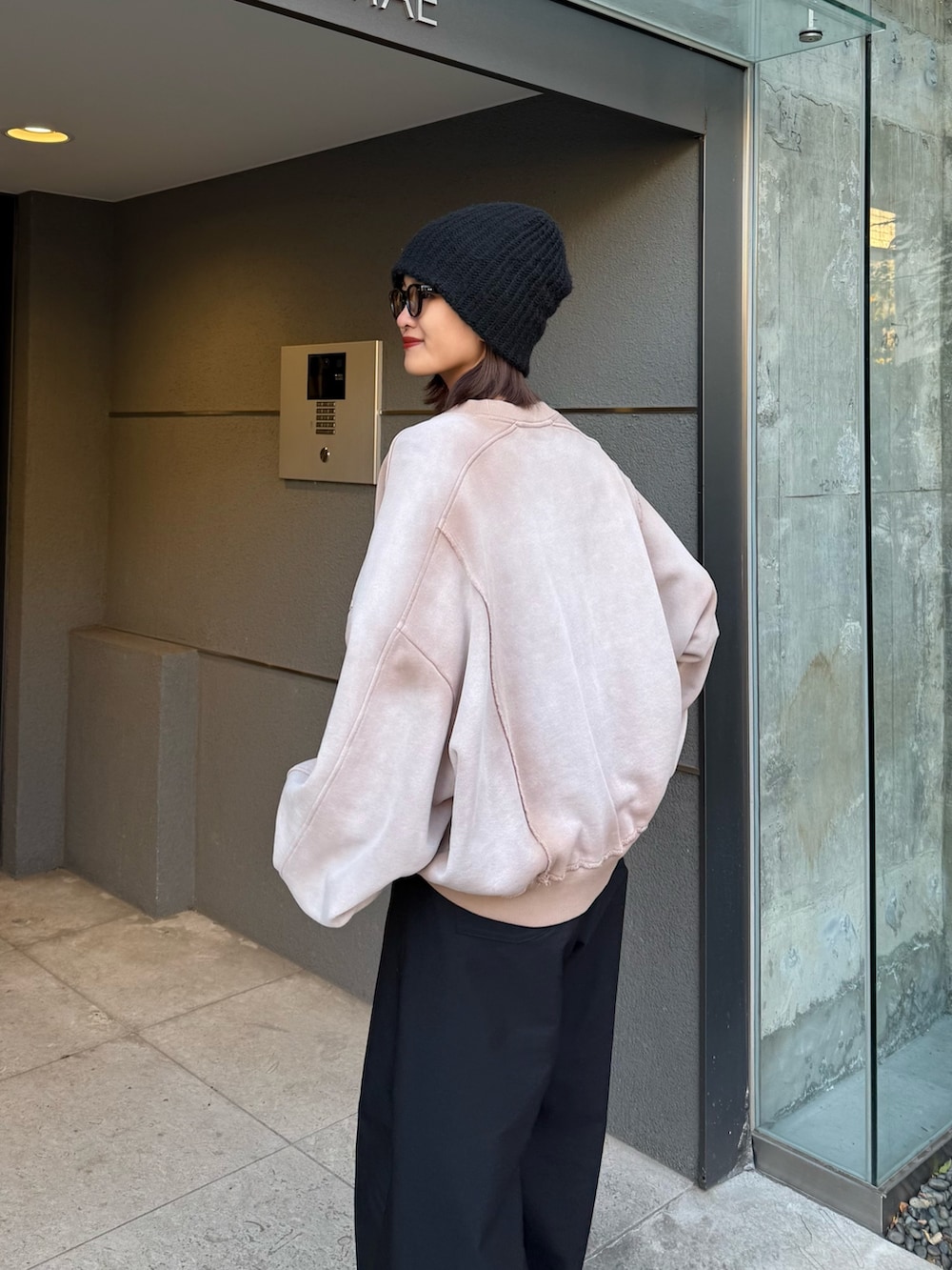 ベージュ系のスウェット、ブラック系のスラックス、ブラック系のサングラスを着用したレディースの冬コーディネートの6枚目の写真