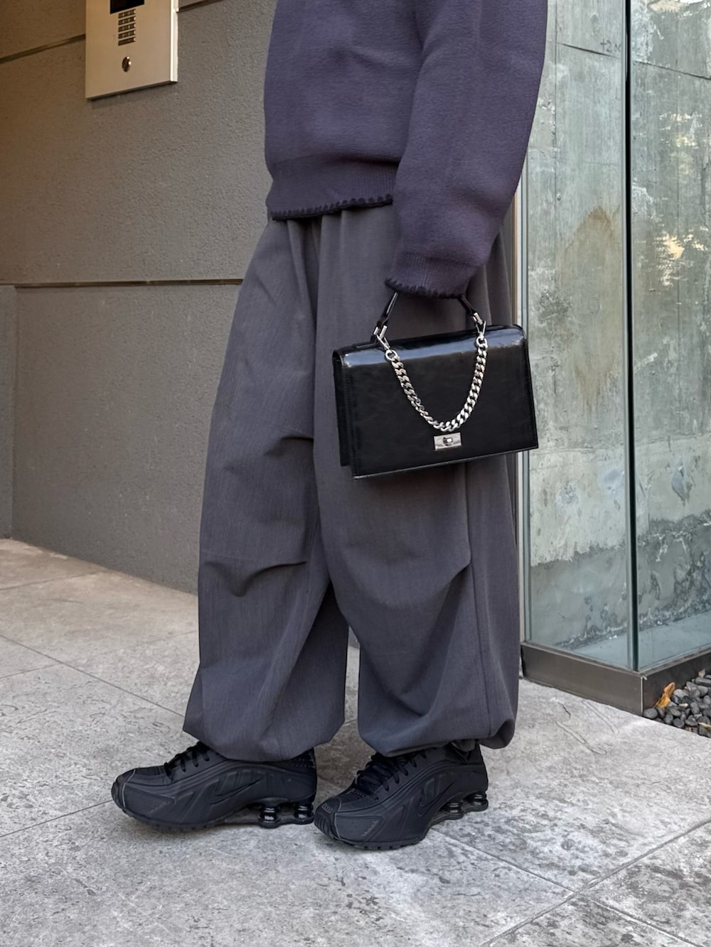 グレー系のニット/セーター、グレー系のスラックス、ブラック系のショルダーバッグを着用したレディースの冬コーディネートの6枚目の写真