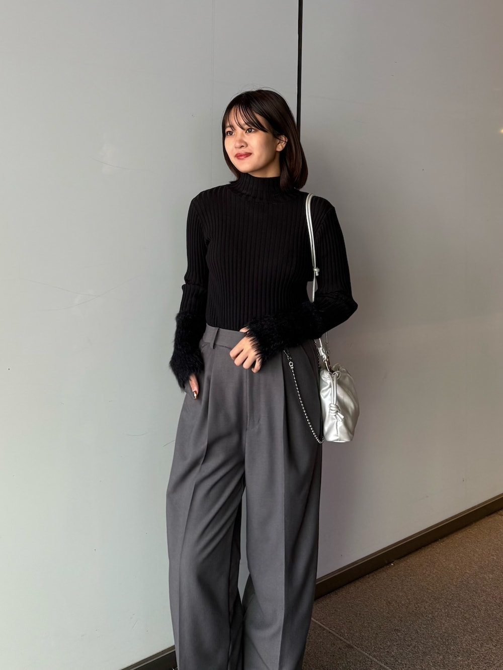 グレー系のスラックス、シルバー系のショルダーバッグ、ブラック系のTシャツ/カットソーを着用したレディースの秋コーディネートの4枚目の写真