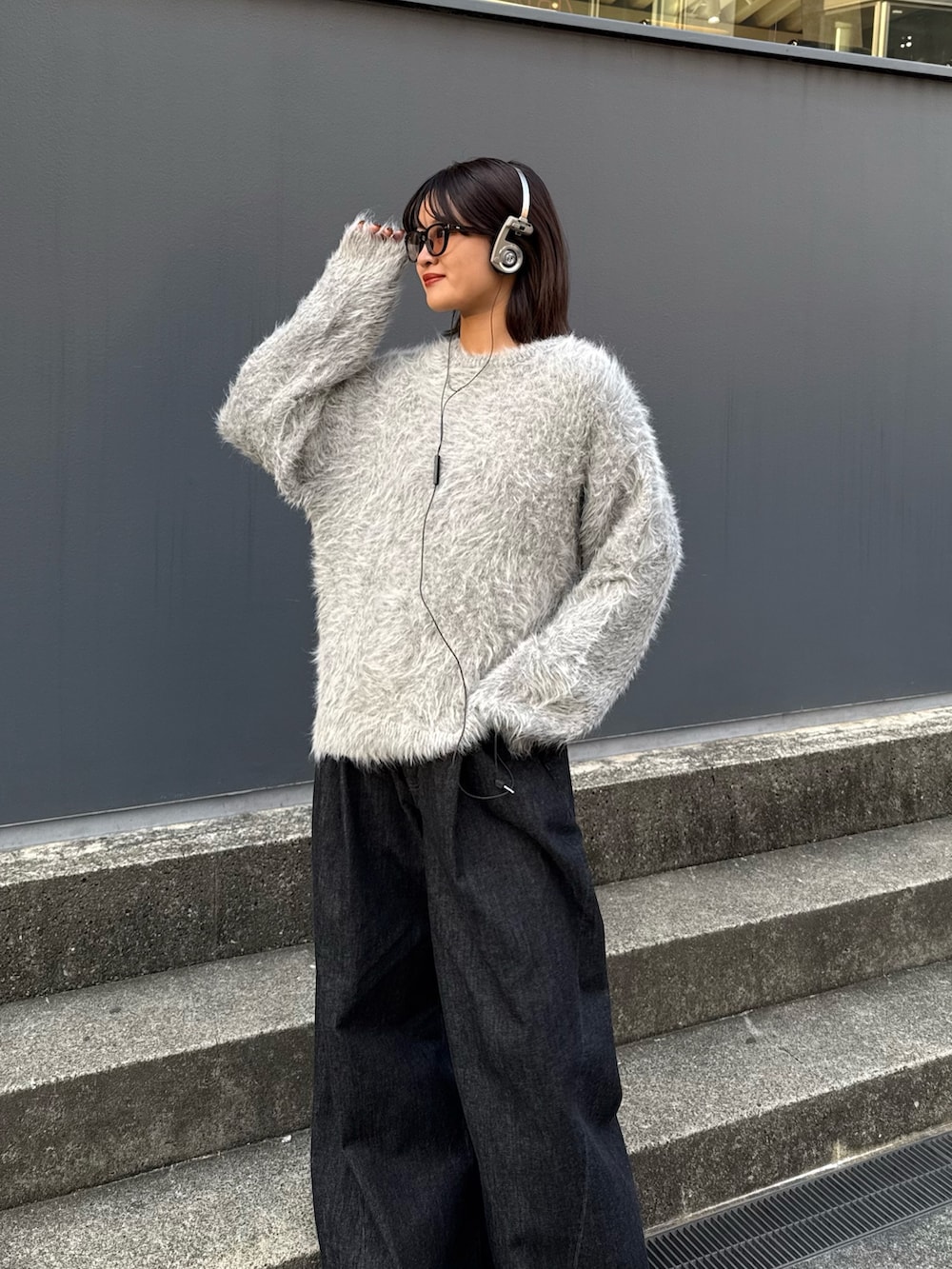 グレー系のニット/セーター、ブラック系のデニムパンツを着用したレディースの秋コーディネートの5枚目の写真