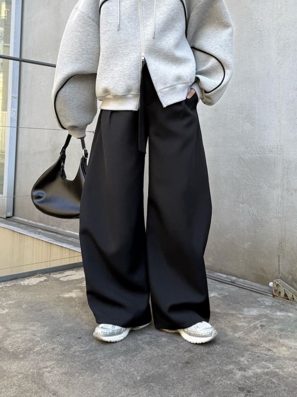 グレー系のパーカー、ブラック系のスラックス、ブラック系のハンドバッグを着用したレディースの冬コーディネートの2枚目の写真