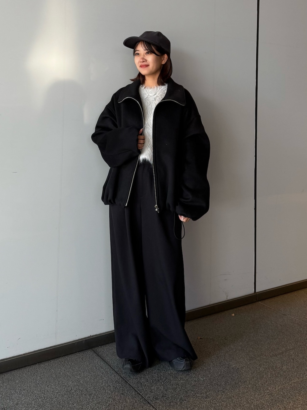 ブラック系のブルゾン、ブラック系のスラックス、グレー系のニット/セーターを着用したレディースの冬コーディネートの2枚目の写真