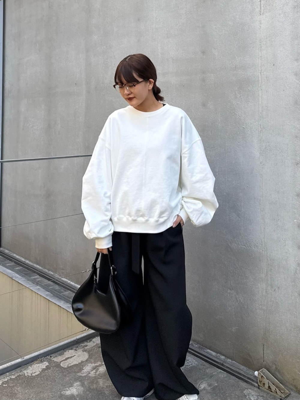 ホワイト系のスウェット、ブラック系のスラックス、ブラック系のハンドバッグを着用したレディースの冬コーディネートの4枚目の写真