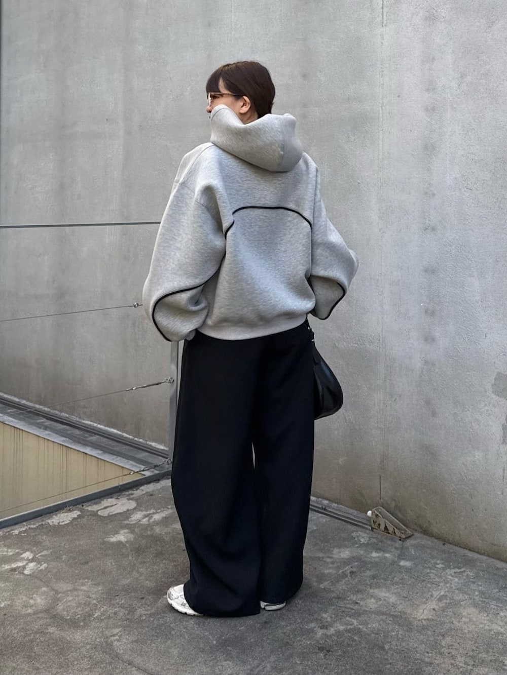 グレー系のパーカー、ブラック系のスラックス、ブラック系のハンドバッグを着用したレディースの冬コーディネートの6枚目の写真