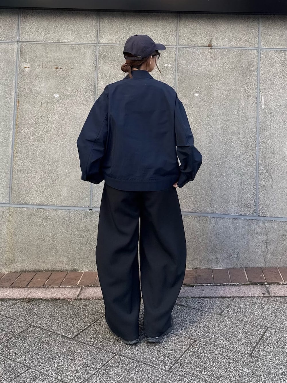 ブラック系のスラックス、ブルー系のブルゾン、ブラック系のサングラスを着用したレディースの冬コーディネートの4枚目の写真