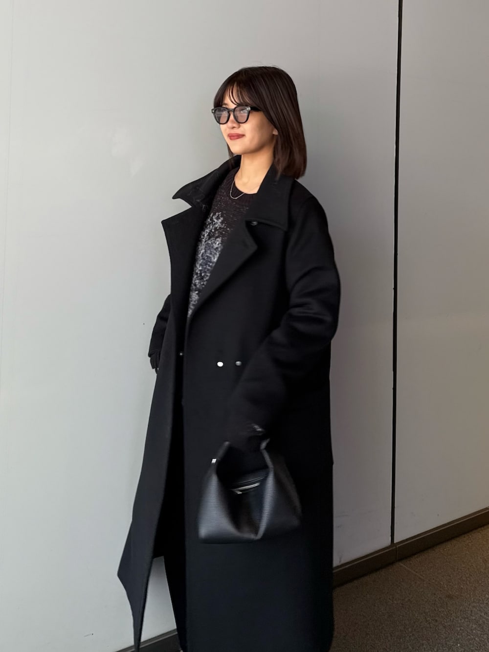 ブラック系のチェスターコート、ブラック系のニット/セーター、ブラック系のトートバッグを着用したレディースの秋コーディネートの6枚目の写真