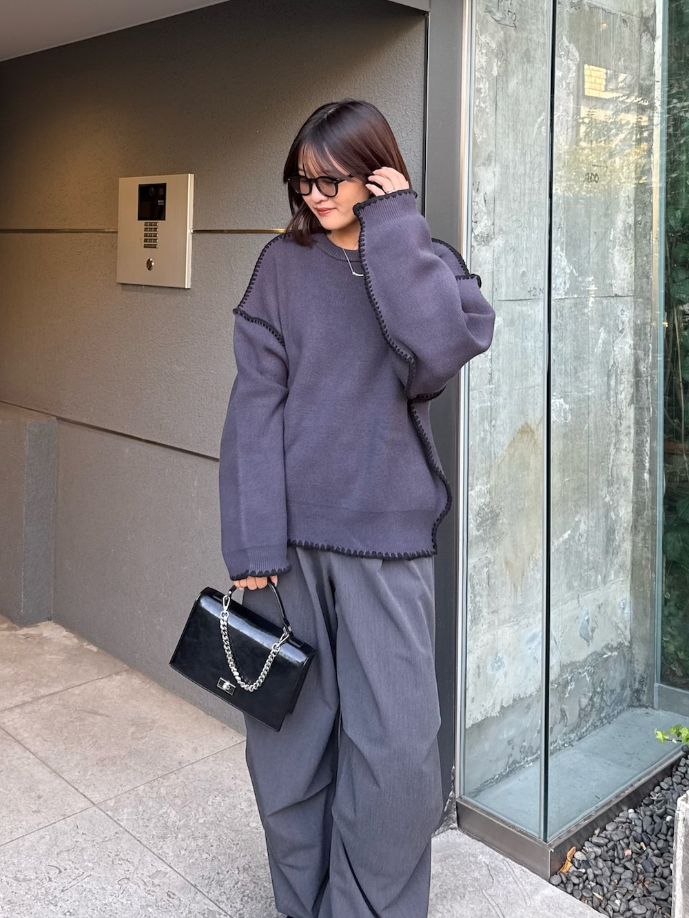 グレー系のニット/セーター、グレー系のスラックス、ブラック系のショルダーバッグを着用したレディースの冬コーディネートの4枚目の写真