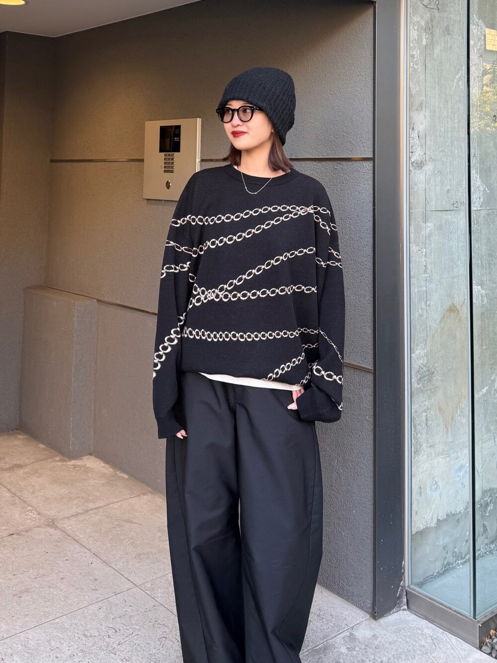 ブラック系のスラックス、ブラック系のニット/セーター、ブラック系のサングラスを着用したレディースの冬コーディネートの2枚目の写真