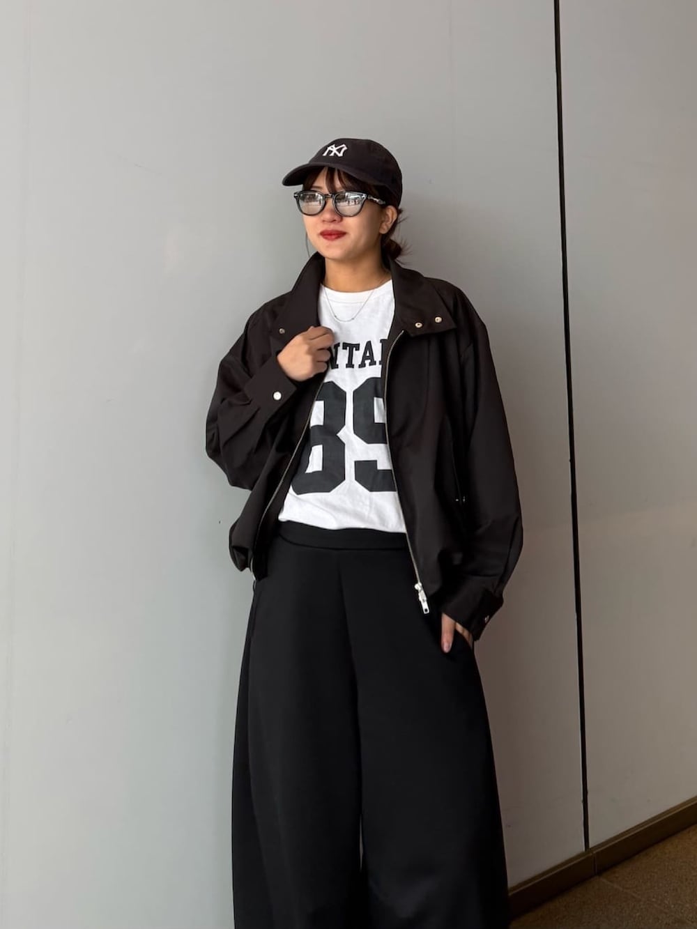 ブラック系のブルゾン、グレー系のその他パンツ、ブラック系のサングラスを着用したレディースの春コーディネートの4枚目の写真