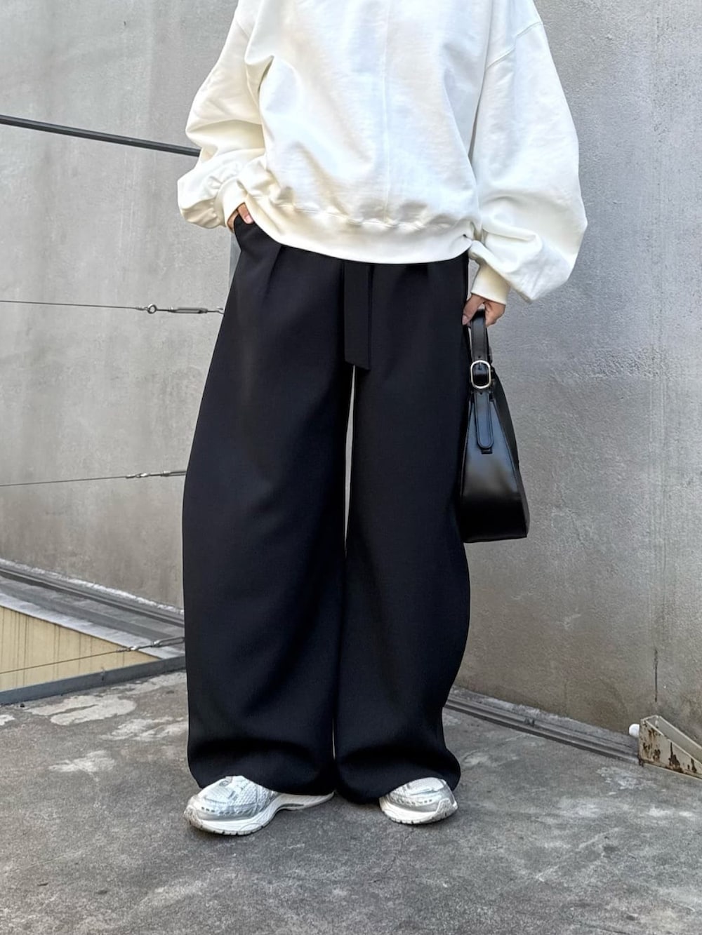 ホワイト系のスウェット、ブラック系のスラックス、ブラック系のハンドバッグを着用したレディースの冬コーディネートの2枚目の写真