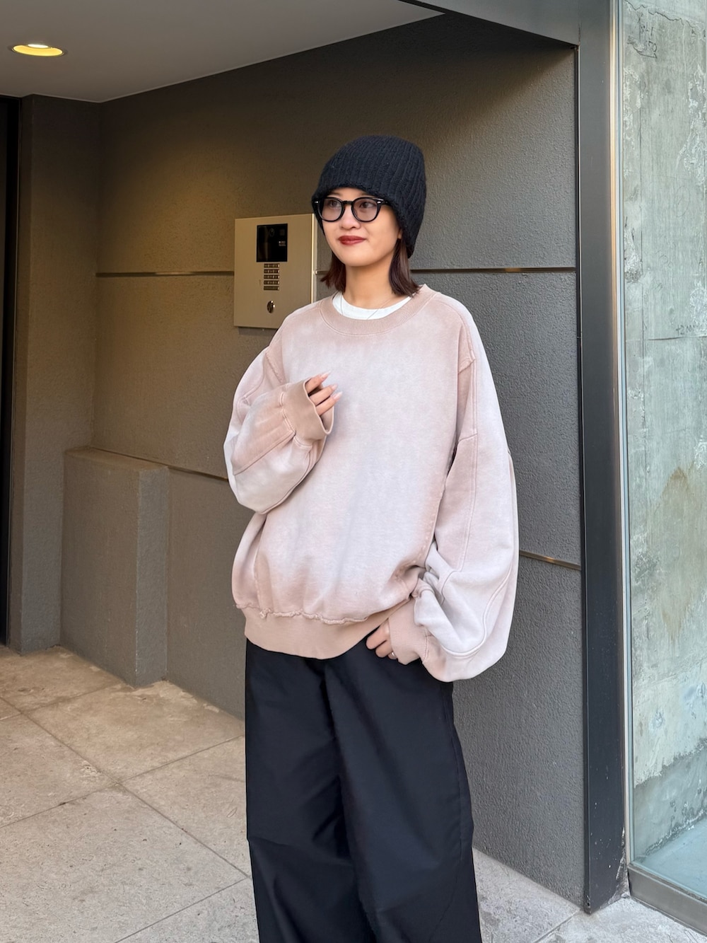 ベージュ系のスウェット、ブラック系のスラックス、ブラック系のサングラスを着用したレディースの冬コーディネートの4枚目の写真