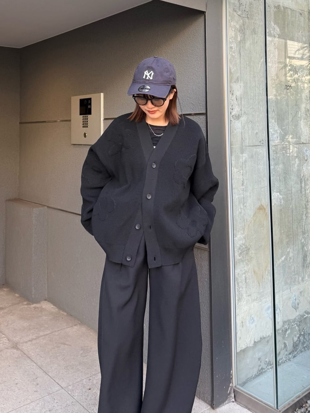 ブラック系のスラックス、ブラック系のカーディガン/ボレロ、ブラック系のサングラスを着用したレディースの冬コーディネートの2枚目の写真